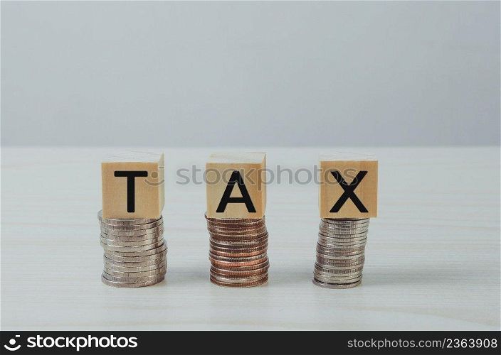 wooden cube block on coins icon TAX business finance Concept.