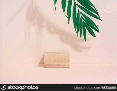 Wooden cube on a beige background with a shadow from a palm leaf. Stage for product demonstration, cosmetics. Promotion and advertising