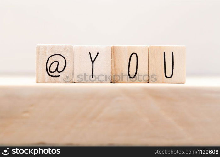 Wooden cube signs with At sign and the word you on white background, tag someone on social media concept closeup. Wooden cube signs with At sign and the word you on white background, tag someone on social media concept