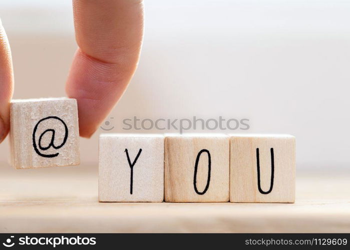 Wooden cube signs with At sign and the word you on white background, tag someone on social media concept closeup. Wooden cube signs with At sign and the word you on white background, tag someone on social media concept