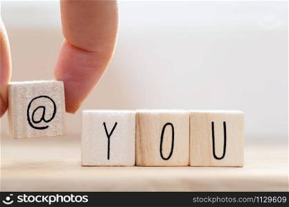 Wooden cube signs with At sign and the word you on white background, tag someone on social media concept closeup. Wooden cube signs with At sign and the word you on white background, tag someone on social media concept