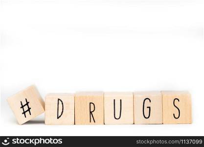 Wooden cube with a hashtag and the word Drugs isolated on white background, social media concept