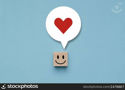 Wooden cube with happy face with a happy in thought in its head, wood block with a emotion smile face and love in thoughts