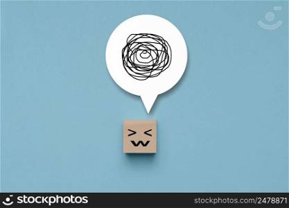 Wooden cube with unhappy face with a tangle of thoughts in its head, wood block with a emotion stress face and confused thoughts , depressed and worry for distress
