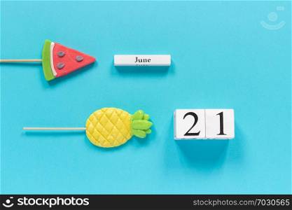 Wooden cubes calendar date June 21st and summer fruits candy pineapple, watermelon lollipops on stick on blue background. Concept vacation or holidays Creative Top view Flat lay Template.. Wooden cubes calendar date June 21st and summer fruits candy pineapple, watermelon lollipops on stick on blue background. Concept vacation or holidays Creative Top view Flat lay Template