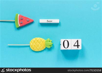 Wooden cubes calendar date June 4th and summer fruits candy pineapple, watermelon lollipops on stick on blue background. Concept vacation or holidays Creative Top view Flat lay Template.. Wooden cubes calendar date June 4th and summer fruits candy pineapple, watermelon lollipops on stick on blue background. Concept vacation or holidays Creative Top view Flat lay Template