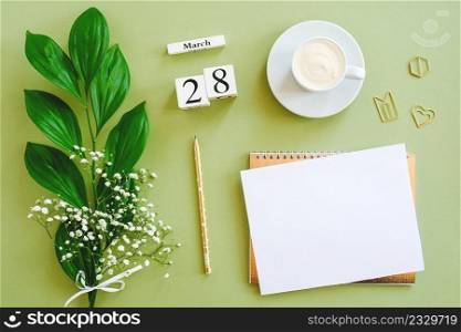 Wooden cubes calendar March 28. Notepad, cup of coffee, bouquet flowers on green background. Concept hello spring Creative Top view Flat lay Mock up.. Wooden cubes calendar March 28. Notepad, cup of coffee, bouquet flowers on green background. Concept hello spring Top view Flat lay Mock up