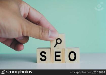 wooden cubes for SEO Search engine optimization magnifying glass icon on background.Copy space.