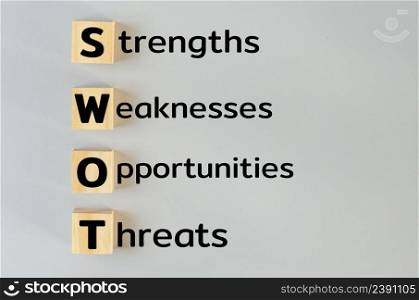 wooden cubes for SWOT strengths weaknesses opportunities threats on gray background.Business marketing Concept