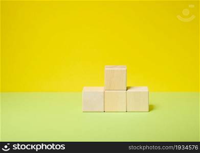 wooden cubes stacked in a pedestal on a yellow-green background, a place to display any product cosmetics, food, drinks, soap