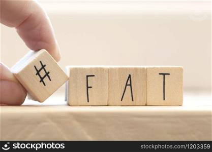 Wooden cubes with a hashtag and the word Fat, social media and health concept background. Wooden cubes with a hashtag and the word Fat, social media and health concept