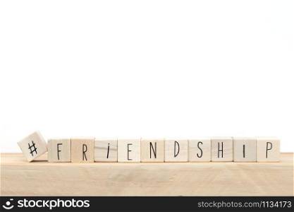 Wooden cubes with a Hashtag and the word friendship near white background, social media concept