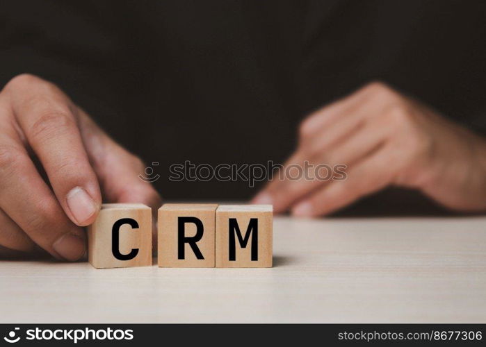 Wooden cubes with CRM Customer relationship management automation system software symbol on desk and copy space.Business concepts.