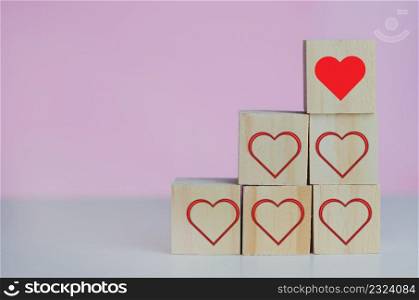 Wooden cubes with love  symbol heart red on the pink background and copy space.