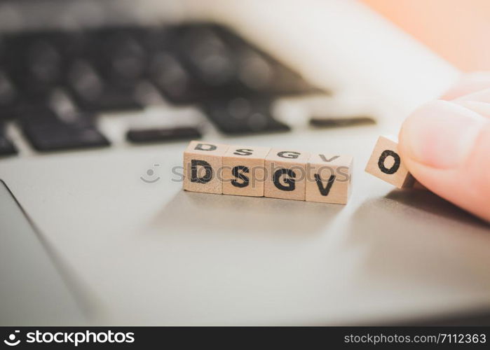 Wooden cubes with the letters ?DGSVO? for Datenschutzgrundverordnung are lying on a laptop