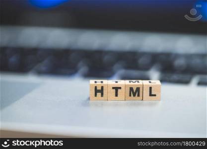 Wooden cubes with the letters ?HTML? are lying on a laptop