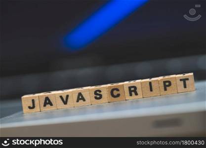 Wooden cubes with the letters ?JAVASCRIPT? are lying on a laptop