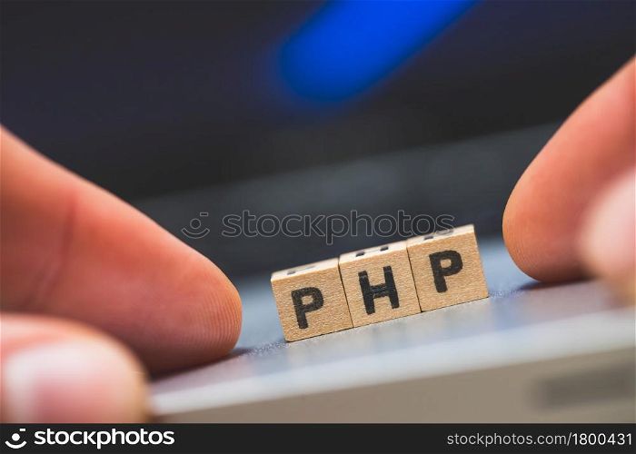Wooden cubes with the letters ?PHP? are lying on a laptop