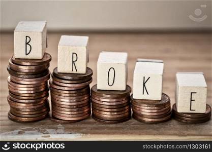 Wooden cubes with the word broke and pile of coins, money climbing stairs, business concept background. Wooden cubes with the word broke and pile of coins, money climbing stairs, business concept
