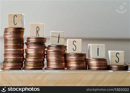 Wooden cubes with the word Crisis and pile of coins, money climbing stairs, business concept background. Wooden cubes with the word Crisis and pile of coins, money climbing stairs, business concept