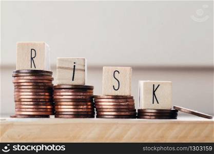 Wooden cubes with the word Risk and pile of coins, money climbing stairs. Business concept background. Wooden cubes with the word Risk and pile of coins, money climbing stairs. Business concept