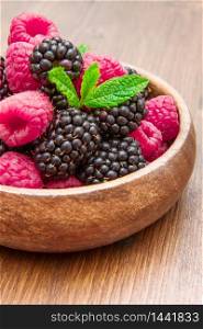 Wooden cup with fresh berries on wooden table