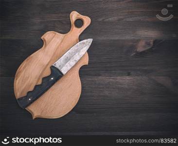 wooden cutting board and old knife on a brown wooden background, empty space on the right