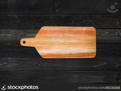 Wooden cutting board on black wood table background. Wooden cutting board isolated on black wood background