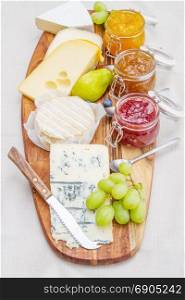 wooden cutting board with cheese and jams