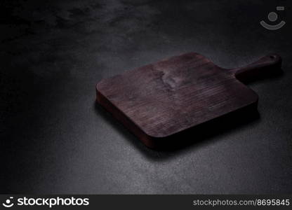 Wooden cutting board with kitchen appliances on a black concrete background. Cooking at home. Wooden cutting board with kitchen appliances on a black concrete background