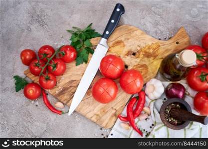 wooden cutting board with knife and tomatoes on grey kitchen concrete or stone table.. wooden cutting board with knife and tomatoes on grey kitchen concrete or stone table