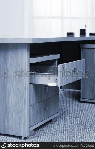 wooden desk with an open drawer in the office