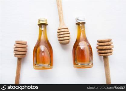 wooden dipper and little honey bottle on white wooden background.