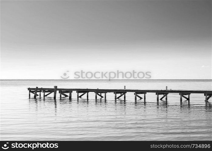 Wooden dock over calm ocean water as minimalism background in stunning black and white