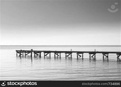 Wooden dock over calm ocean water as minimalism background in stunning black and white