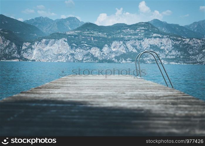 Wooden dock pier, mountains and lake. Copy space for text.