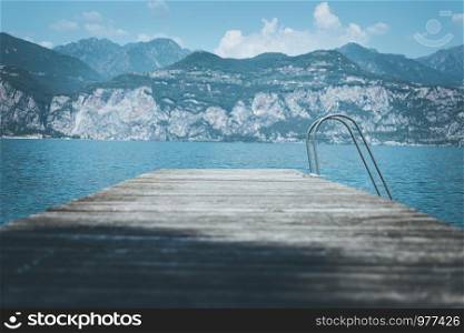 Wooden dock pier, mountains and lake. Copy space for text.