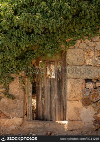 Wooden door opening into garden of stone house in the ancient town of Castelo Rodrigo in Portugal. Old wooden door into ancient homes in Castelo Rodrigo in Portugal