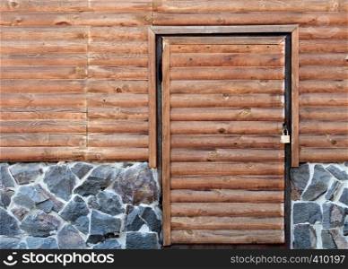 Wooden door to the back room of the log house and a stone foundation. Wooden door to the utility room of a house standing on a stone foundation