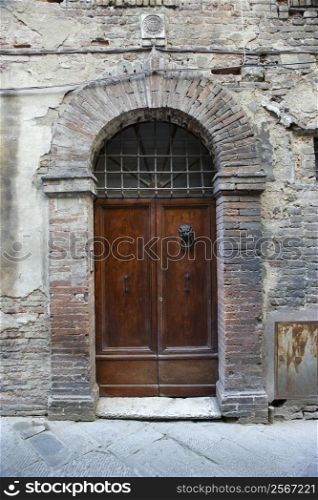 Wooden door with brick archway, Italy.