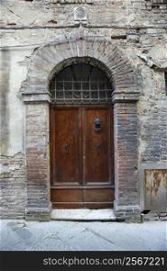 Wooden door with brick archway, Italy.