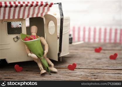 Wooden dummy hugging bouquet of roses in the car with space to write. Valentine concept, Vintage tone, AF point selection.