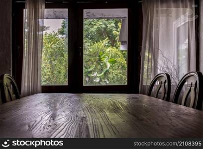 Wooden eating table and chairs in dining room. Wooden window and white curtains in traditional house, No focus, specifically.