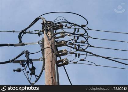 Wooden electric power pole on blue sky background
