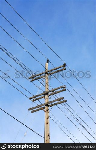 Wooden electrical transmission pole and power lines against sky.