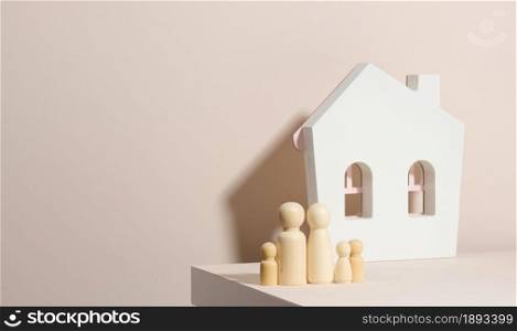 wooden family figurines, model house on a beige background. Real estate purchase, rental concept. Moving to new apartments