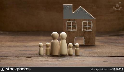 wooden family figurines, model house on a brown background. Real estate purchase, rental concept. Moving to new apartments