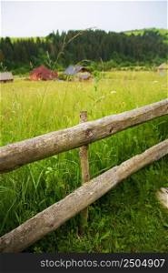 Wooden fence against the summer landscape in the Ukrainian Carpathian Mountains.. Carpathian nature in summer
