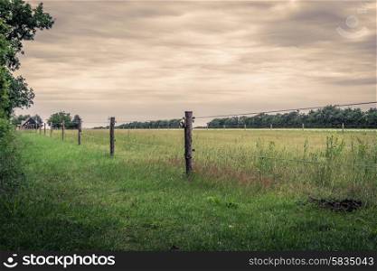 Wooden fence on a green field in cloudy weather