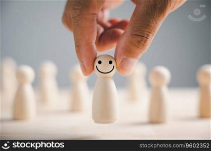 Wooden figure with happy face hand picked from crowd. Customer service rating experience feedback. HR management choosing positive leader to motivate team towards satisfaction and success in business